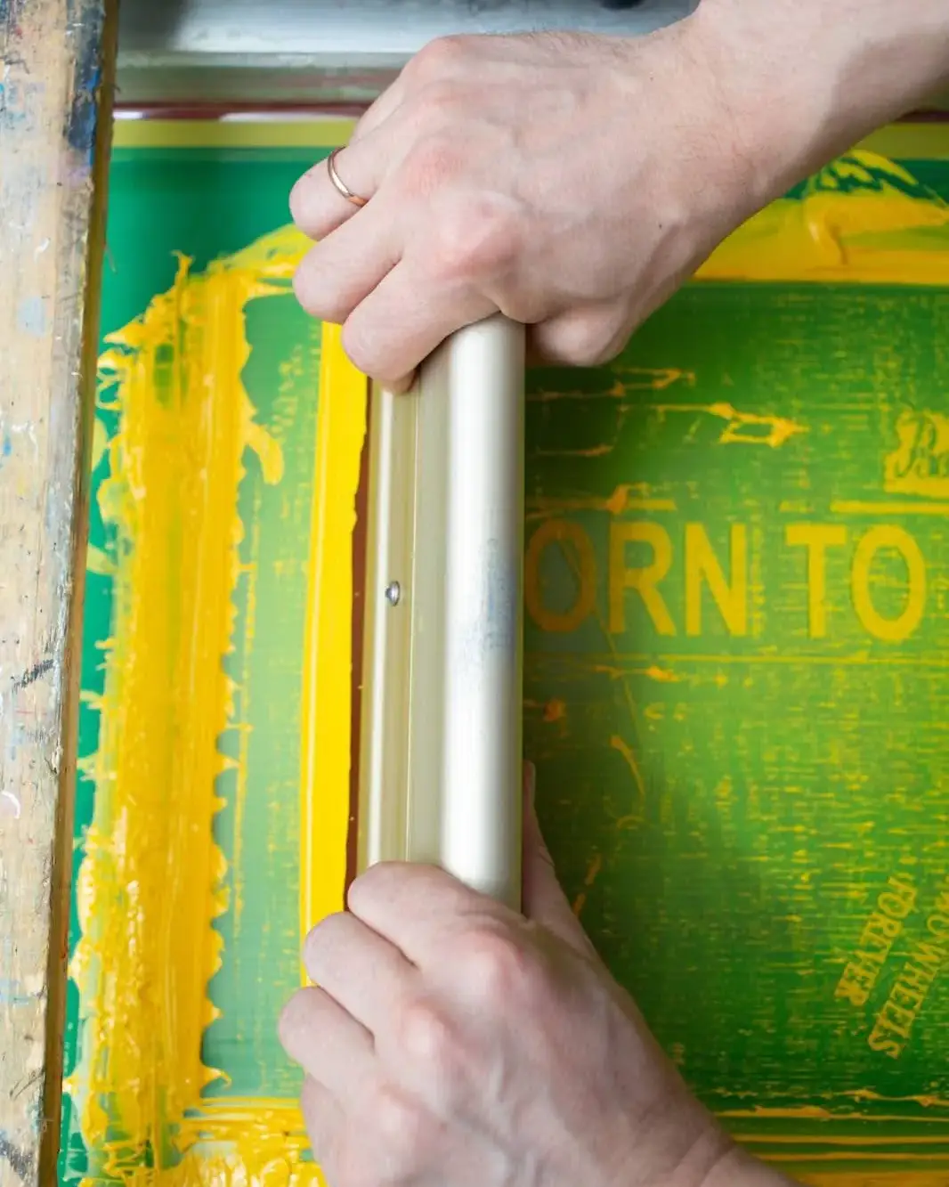 Professional Screen Printing on T-Shirt with Yellow Paint Screen printing process: Yellow paint is precisely applied to a T-shirt using a stencil and squeegee in a textile print shop