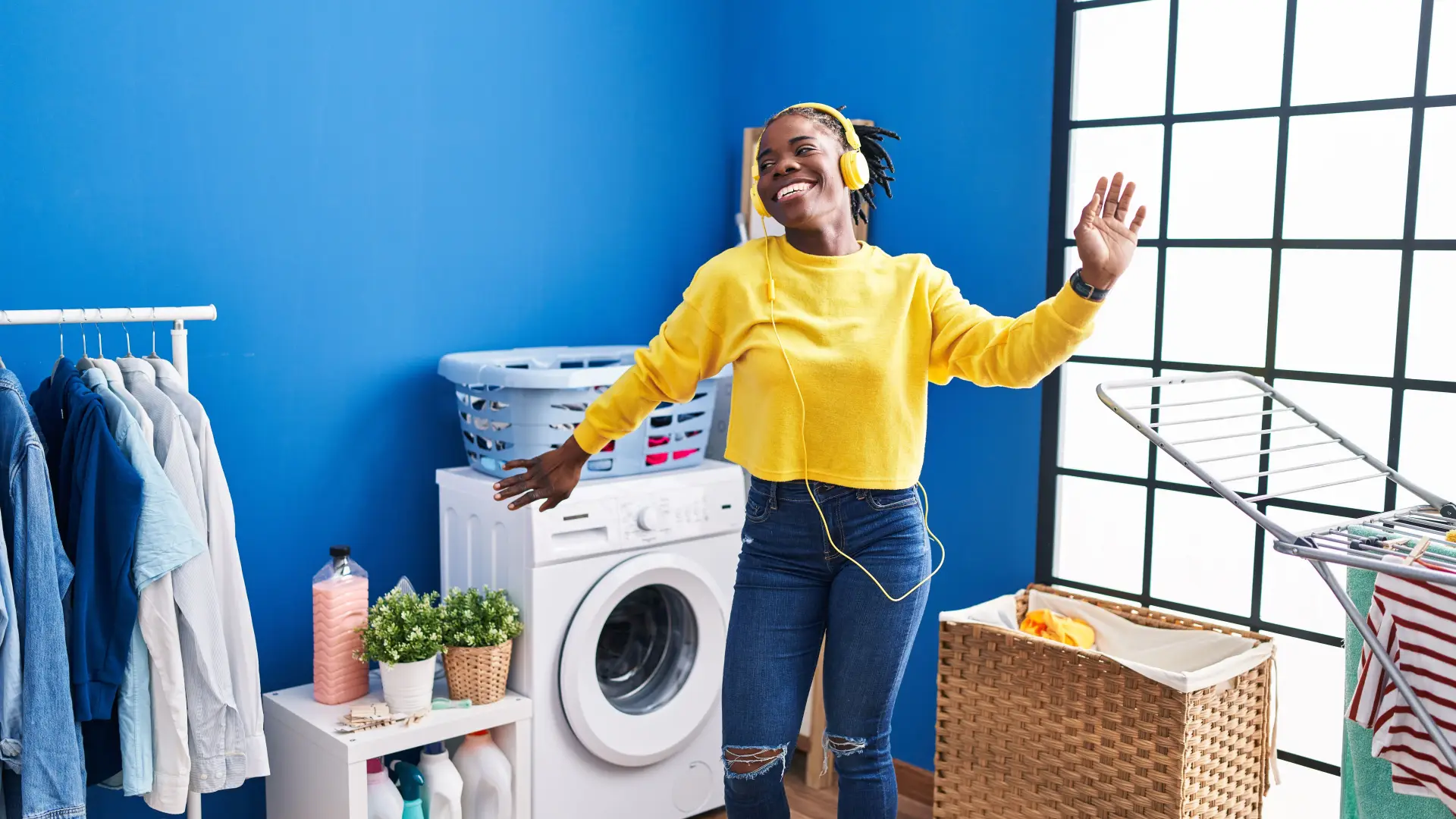Woman waiting at the laundromat – care for printed T-shirts Woman listening to music while doing laundry – tips for caring for personalized clothing
