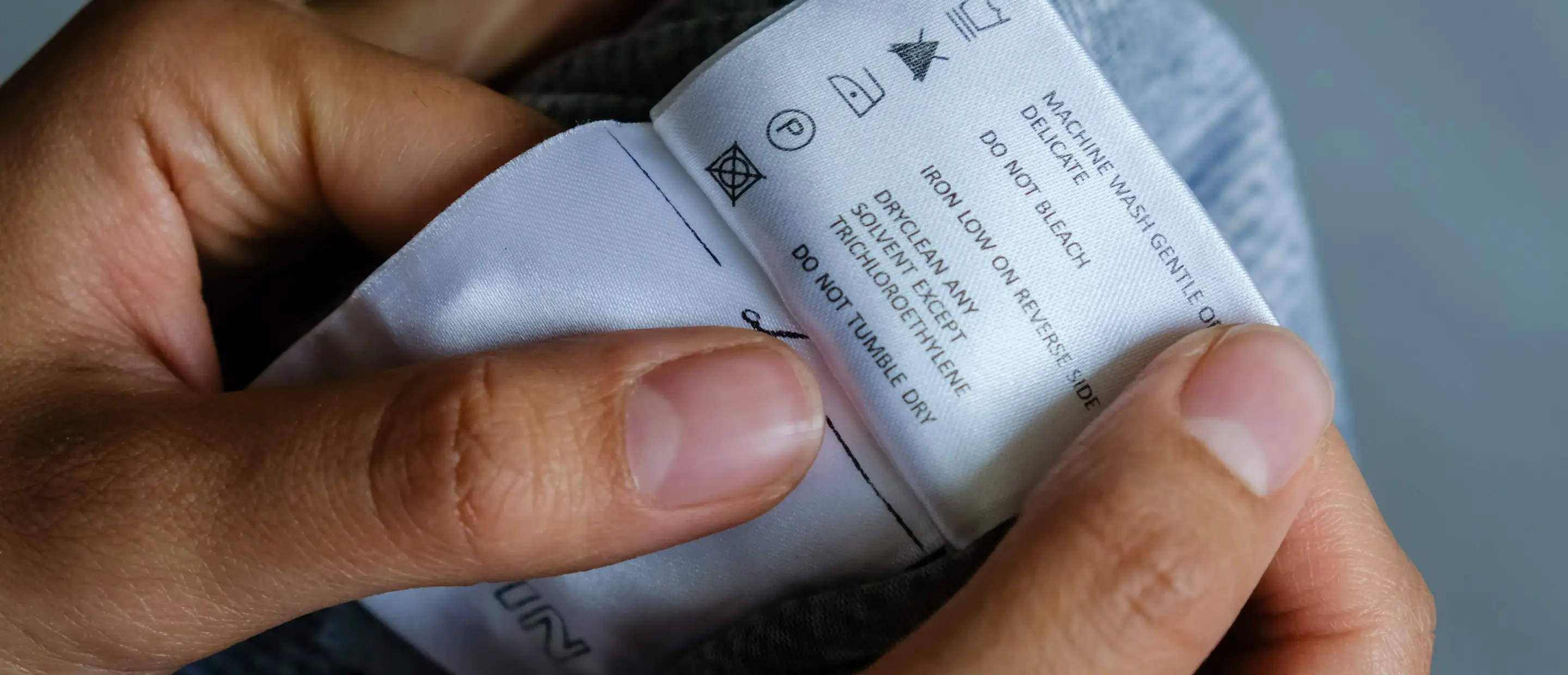 Clothing label with care instructions – close-up Hands holding a clothing label with care instructions like washing, ironing, and cleaning – close-up of textile tag