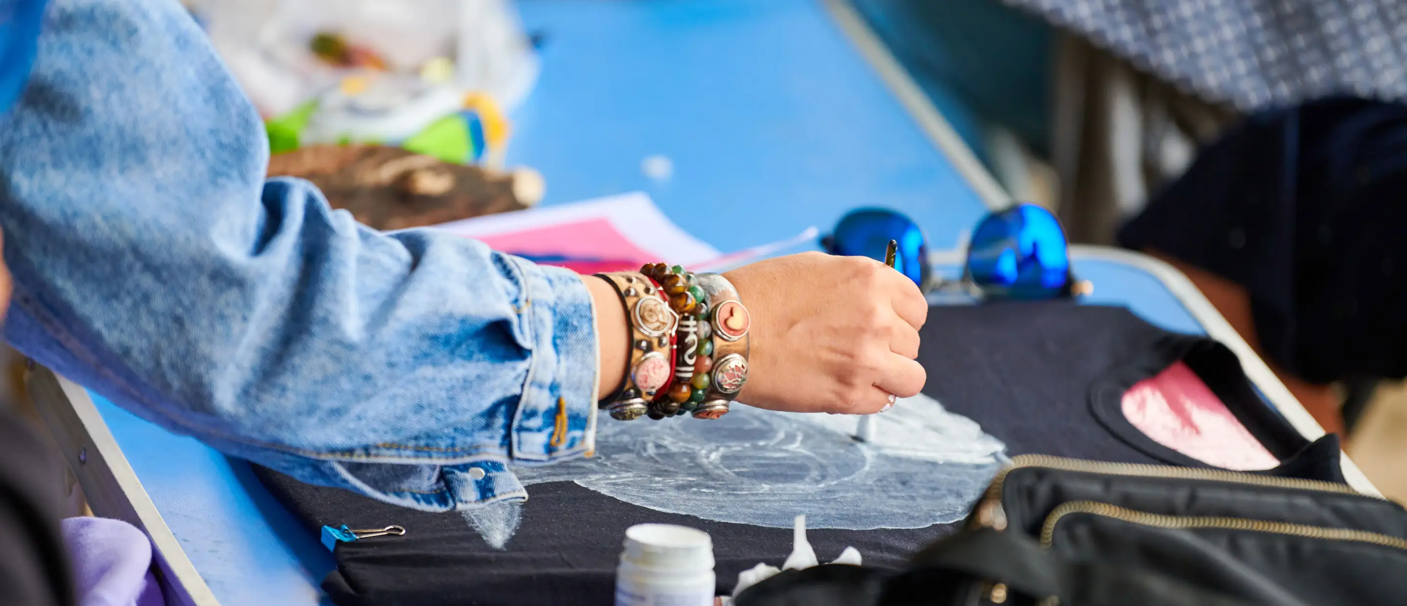 Creative & Colorful – How to Customize Your T-Shirts! A woman customizes a black T-shirt by hand using a brush and fabric paint in a workshop – abstract DIY-style design